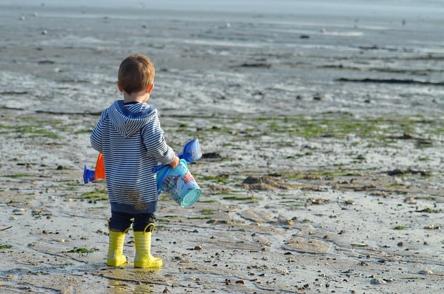 Kind mit Stiefel am Strand